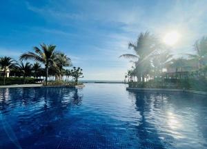 - une piscine avec des palmiers et l'océan dans l'établissement Mystery Villas & Spa Cam Ranh, à Cam Lâm