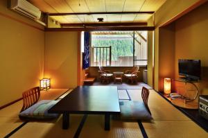 a living room with a table and chairs and a television at Sunriver Oboke in Miyoshi