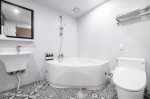 a bathroom with a tub and a toilet and a sink at Java Hotel in Gwangyang