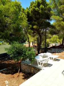 un grupo de mesas y sillas blancas en un parque en Studio apartment Under the pine, en Milna