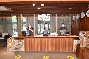 three people wearing face masks standing at a counter at Prince Hotel in Yangon