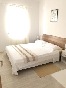 - une chambre blanche avec un grand lit et une fenêtre dans l'établissement Apartment Kozarica 4950b, à Kozarica