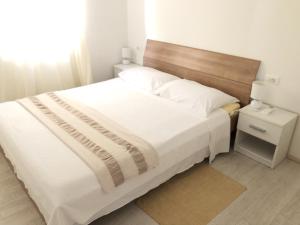 a bedroom with a large bed with a wooden headboard at Apartment Kozarica 4950b in Kozarica