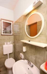 bagno con lavandino, servizi igienici e specchio di Apartment Mundanije 5072b a Rab