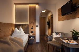 ein Hotelzimmer mit einem Bett und einem Tisch in der Unterkunft Almhotel Lenz in Olang