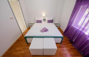two beds in a small room with purple curtains at Apartment Palit 4971a in Rab