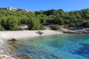 a boat in the water on a rocky beach at Apartment Rukavac 8864b in Rukavac