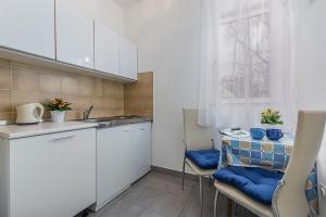 een keuken met een wastafel en een tafel met blauwe kussens bij Studio Novigrad 2536a in Novigrad Istria
