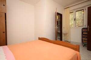 ein Schlafzimmer mit einem Bett mit einer orangefarbenen Decke in der Unterkunft Apartment Tucepi 6857a in Tučepi