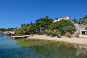 a beach with a building and trees and water at Apartment Vidalici 6519f in Kustići