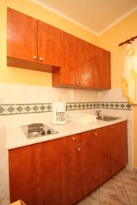 uma cozinha com armários de madeira e um lavatório em Apartment Stara Novalja 6469b em Novalja