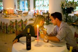 mężczyzna i kobieta siedzący przy stole ze świecą w obiekcie Hotel Panoramic w Caorle
