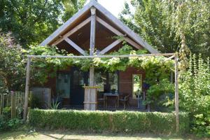 a wooden pergola with a table in a garden at Tijdzat in Haaren