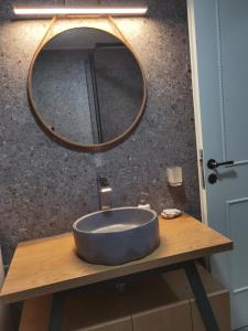 ein Waschbecken im Bad mit einem runden Spiegel auf dem Tisch in der Unterkunft Blue in Nydri