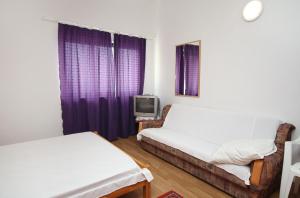 a room with two beds and a tv and purple curtains at Studio Drvenik Gornja vala 4890e in Drvenik
