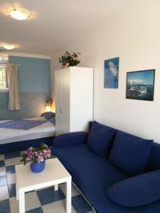 a living room with a blue couch and a bed at Studio Banjol 5071a in Rab