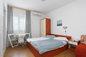 a bedroom with a bed and a red chair at Studio Tucepi 6695a in Tučepi