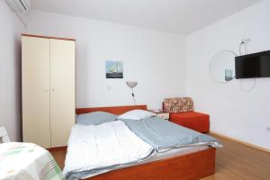 a bedroom with a bed and a chair at Studio Tucepi 6695a in Tučepi