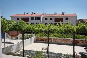 a row of trees in front of a building at Double Room Palit 5061a in Rab