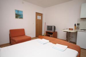 um quarto com uma cama, uma cadeira e uma televisão em Studio Makarska 6696a em Makarska