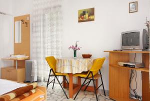 a dining room with a table and yellow chairs at Studio Selce 4801a in Selce
