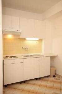 uma cozinha vazia com armários brancos e um lavatório em Studio Tucepi 6857c em Tučepi
