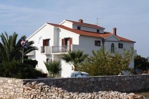a white house behind a stone wall at Triple Room Gornje selo 5170d in Grohote