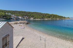 a sandy beach with a house and the water at Triple Room Gornje selo 5170d in Grohote +9 photos