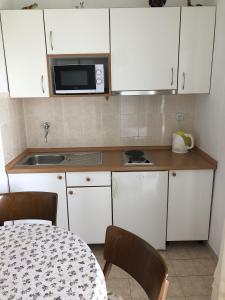 a kitchen with white cabinets and a table and a microwave at Studio Tucepi 6901a in Tučepi