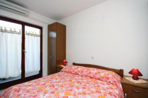 ein Schlafzimmer mit einem Bett mit einer farbenfrohen Tagesdecke und einem Fenster in der Unterkunft Double Room Palit 5044b in Rab