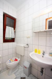 a white bathroom with a toilet and a sink at Double Room Palit 5044b in Rab