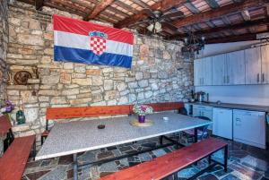 une cuisine avec une table et un drapeau sur un mur en pierre dans l'établissement Twin Room Tisno 5128a, à Tisno