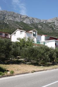una casa bianca sul ciglio di una strada con una montagna di Double Room Gradac 6819a a Gradac (Grado)