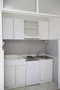 a white kitchen with white cabinets and a sink at Studio Tucepi 6857b in Tučepi