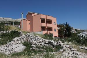a building on top of a hill with rocks at Double Room Metajna 6487d in Metajna +11 photos