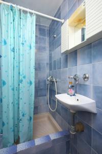 Baño de azulejos azules con cortina de ducha y lavamanos en Double Room Sucuraj 6734b, en Sućuraj