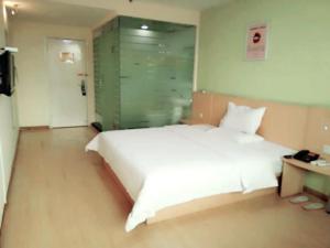 um quarto com uma grande cama branca e uma parede de vidro em 7Days Inn Xi'an Northwest University North Gate em Xi'an