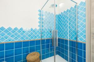 a blue tiled shower with a glass door at Sa Domm'e Galleria in Baunei