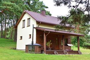 uma pequena casa branca com um alpendre em Holiday Homes Eliza em Druskininkai