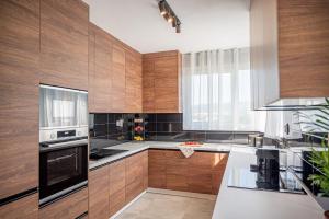 a kitchen with wooden cabinets and a large window at Apartmány pod Zámkom in Bojnice
