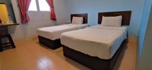 two beds in a bedroom with a window at Dream House Hotel in Skudai