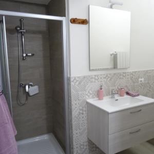 uma casa de banho com um chuveiro, um lavatório e um espelho. em Appartamento ROSA - Colori del Lago d'Orta - NUOVA STRUTTURA A OMEGNA em Omegna