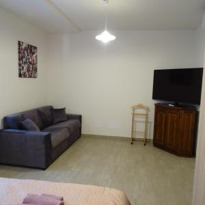 uma sala de estar com um sofá e uma televisão de ecrã plano em Appartamento ROSA - Colori del Lago d'Orta - NUOVA STRUTTURA A OMEGNA em Omegna