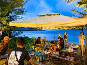 a group of people sitting at tables under a large umbrella at Le Grand Bleu in Amami