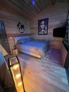ein Schlafzimmer mit einem Bett in einem Holzzimmer in der Unterkunft Les Fermes de Manat gîte romantique avec piscine balnéo et sauna 