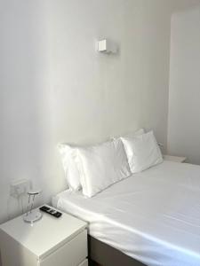 Cama blanca con almohadas blancas y mesita de noche en Easy Milano - Rooms and Apartments Navigli en Milán