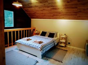 1 dormitorio con cama y techo de madera en Ranczo w lesie - domki z jacuzzi en Ożarów