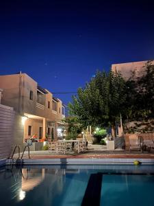 una piscina di fronte a una casa di notte di Nikolas Apartments ad Amoudara Herakliou