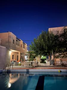 a swimming pool in front of a house at night at Nikolas Apartments in Amoudara Herakliou