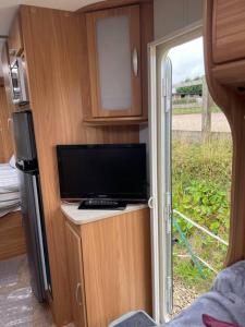 uma caravana com uma televisão e uma porta de vidro deslizante em Inviting 4 Berth caravan in Hebden Bridge em Halifax